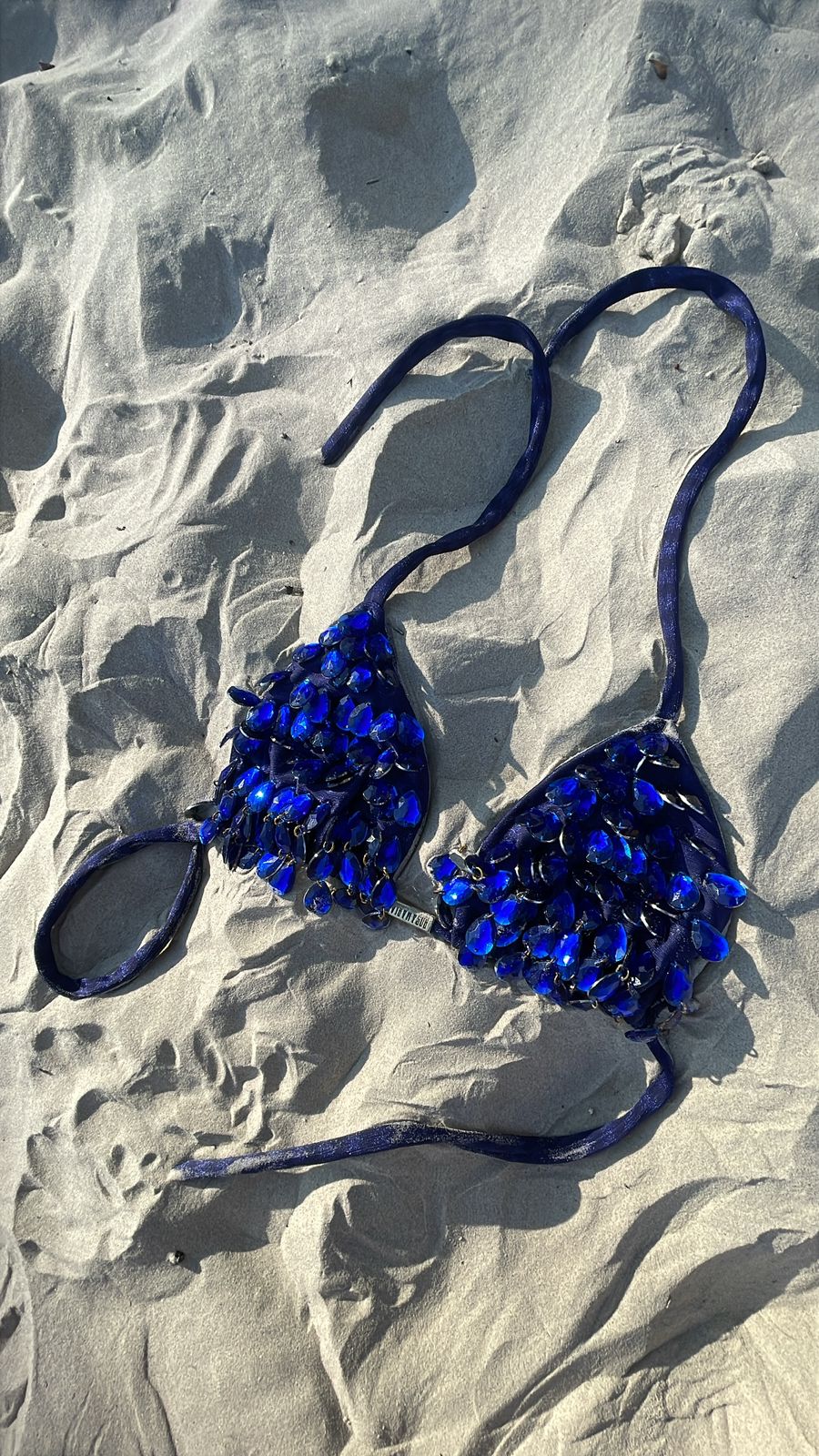 Blue glass necklace on sandy surface